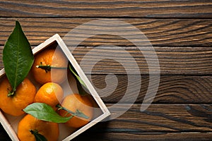 Fresh tangerines with leaves in wooden box on the table