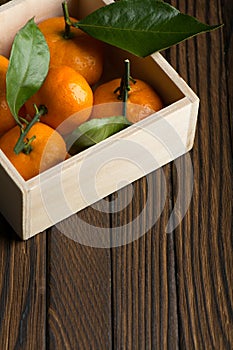 Fresh tangerines with leaves in wooden box on the table