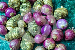 Fresh taro roots and onions on green marble texture background