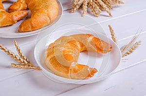 Fresh tasty bagel with filling on white plate on wooden background