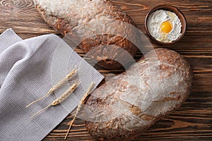 Fresh tasty bread and bowl with white flour on wooden background