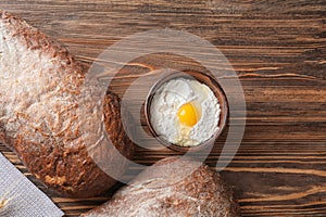 Fresh tasty bread and bowl with white flour on wooden background