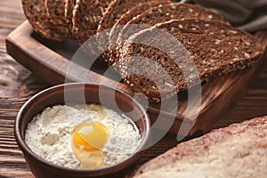 Fresh tasty bread and bowl with white flour on wooden table