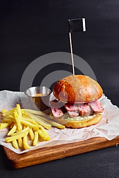 Fresh tasty burger on black background, served with sauce and french fries. Fast food, junk food concept.