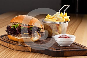 Fresh tasty burger and french fries on wooden table