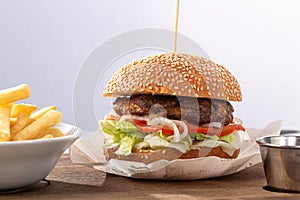 Fresh tasty burger and french fries on wooden table