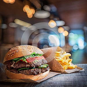 Fresh tasty burger and french fries on wooden table.