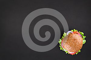 Fresh tasty burger Top view on black background. Tasty and appetizing cheeseburger. Vegetarian burger with place for