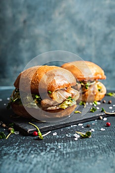 Fresh tasty burgers with roasted chicken, potato, micro greens and different herbs on the rustic background