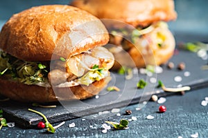 Fresh tasty burgers with roasted chicken, potato, micro greens and different herbs on the rustic background