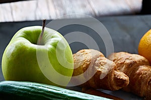 Fresh tasty croissants with apple on dark cutting board, close-up, selective focus