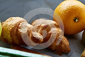 Fresh tasty croissants with apple on dark cutting board, close-up, selective focus