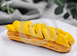 Fresh tasty eclair on white plate closeup