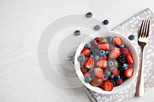 Fresh tasty fruit salad on white wooden table, flat . Space for text