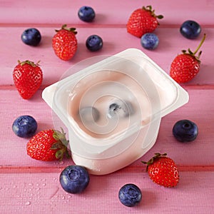 Fresh tasty yogurt and strawberries and blueberries on wooden background. Healthy Breakfast Concept