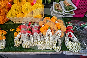 Fresh Thai style flower garlands made of white jasmine, crown flower, red rose and yellow marigold with betel nut tray