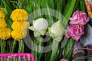 Fresh Thai style temple offering flower sets made of white and pink lotus flower, yellow marigold with green pandan leaves