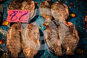 Fresh tilapia are scaled, gutted and put on a plate for sale at a fresh market photo