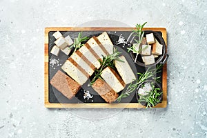 Fresh tofu cheese. Smoked tofu cheese with spices cut into pieces on a board. Vegan healthy food.