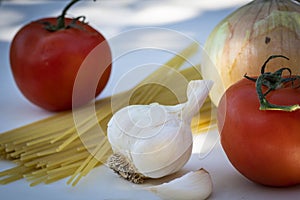 A Fresh Tomato with Garlic and Uncooked Spaghetti