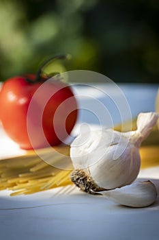 A Fresh Tomato with Garlic and Uncooked Spaghetti