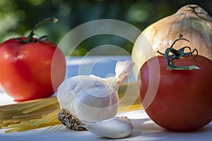 A Fresh Tomato with Garlic and Uncooked Spaghetti