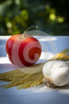 A Fresh Tomato with Garlic and Uncooked Spaghetti