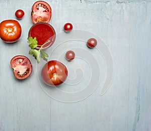 Fresh tomato juice in a glass with a straw, with green leaf, chopped tomatoes spread around border ,text area wooden rusti