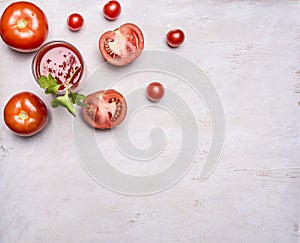 Fresh tomato juice in a glass with a straw, with green leaf, chopped tomatoes spread around border ,text area wooden rusti
