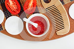 Fresh tomato puree in a small white bowl, coton pads and wooden hair brush. Homemade face or hair mask, natural beauty treatment