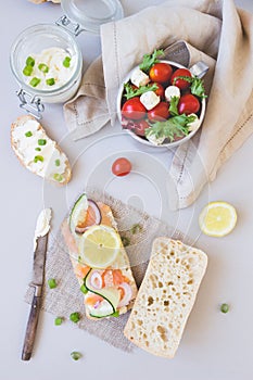 Fresh tomato salad and ciabatta bread with cream cheese and salmon on the gray background