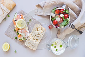 Fresh tomato salad and ciabatta bread with cream cheese and salmon on the gray background