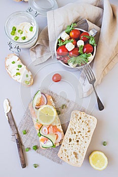 Fresh tomato salad and ciabatta bread with cream cheese and salmon on the gray background