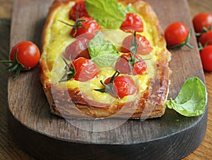 Fresh tomato tart, puff pastry topped with ricotta, cheese and cherry tomatoes