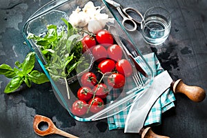 Fresh tomatoes with basil garlic and sea salt on black slate background