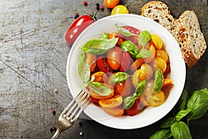 Fresh tomatoes with basil leaves in a bowl