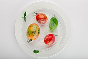 Fresh tomatoes and basil leaves in a white ceramic plate