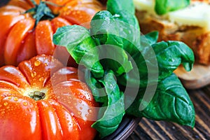 Fresh tomatoes with basil for use as cooking ingredients with copy space. Tomatoes with basil on wooden table background.