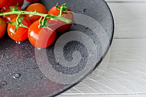 Fresh tomatoes on black plate