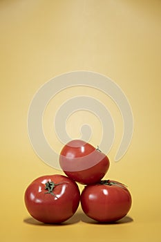 Fresh tomatoes on a bright yellow background in an advertising food photo style.