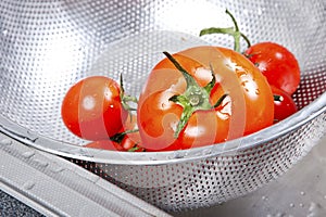 Fresh tomatoes in colander splashing in water