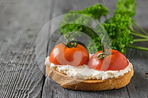 Fresh tomatoes with cottage cheese on a piece of bread on a wooden table.