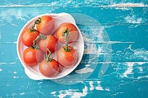 Fresh tomatoes on a green stem on blue background