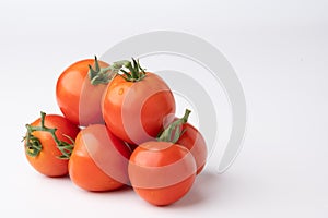 Fresh tomatoes on a green stem on white