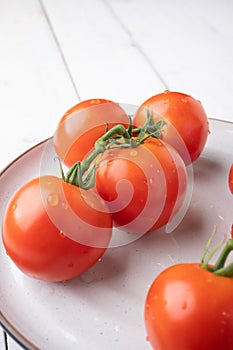 Fresh tomatoes on a green stem on white background