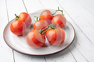 Fresh tomatoes on a green stem on white background