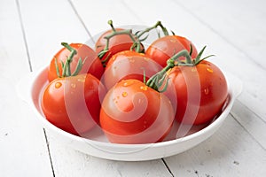 Fresh tomatoes on a green stem on white background