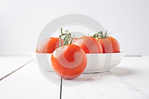 Fresh tomatoes on a green stem on white background