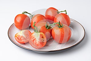 Fresh tomatoes on a green stem on white background
