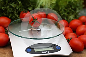 Fresh tomatoes on kitchen scales weighing